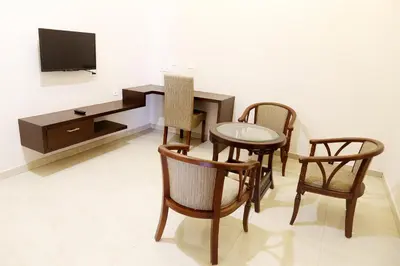 a living room with a table and chairs and a tv at Rydges Inn in Kottakkal