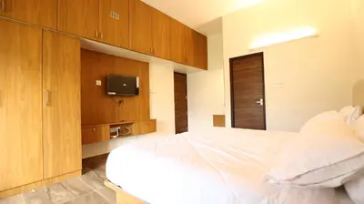 a bedroom with a white bed and a tv at Mira Homestay in Kodaikānāl