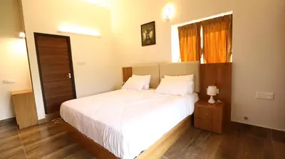 a bedroom with a large white bed and a window at Mira Homestay in Kodaikānāl