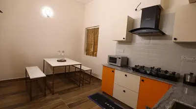 a small kitchen with a table and a microwave at Mira Homestay in Kodaikānāl