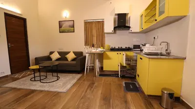 a kitchen and a living room with yellow cabinets at Mira Homestay in Kodaikānāl
