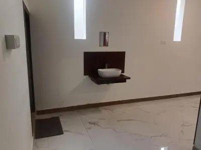 a bathroom with a white wall with a sink at Riverside inn in Wayanad