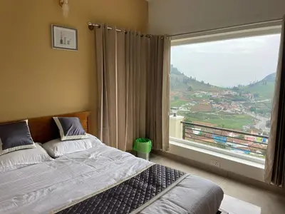 a bedroom with a bed and a large window at May Flower Cottage in Ooty