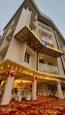 a building with a restaurant with white chairs and lights at Stay Bridge Residency in Kozhikode