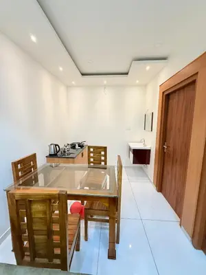 a dining room with a table and chairs and a kitchen at Stay Bridge Residency in Kozhikode