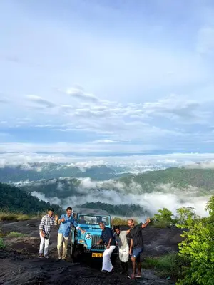 a group of people standing around a blue car on a hill at Mamalakandam - Egg House - in Diya Homestay in Mamalakandam