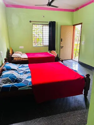 two beds in a room with two red sheets at Yash Residency in Mysore