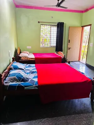 two beds in a bedroom with red sheets at Yash Residency in Mysore