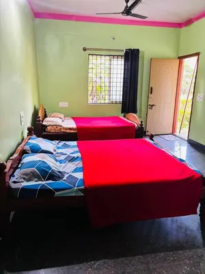 two beds in a bedroom with red sheets on them at Yash Residency in Mysore