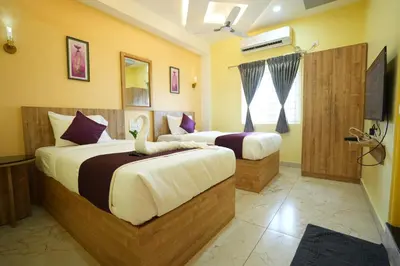 a bedroom with two beds and a television in it at M M Hotel Royal Respite in Coimbatore