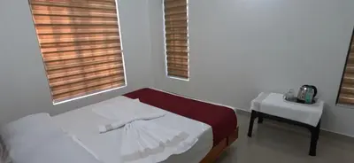 a bed in a room with a table and a chair at Smile Residency in Sultan Bathery