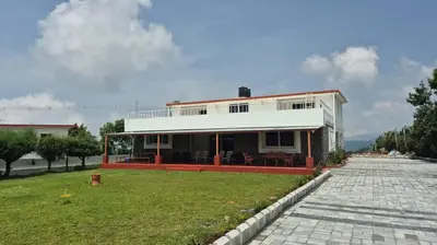a large white house with a lawn in front of it at Mountain Top Holiday Home in Ooty