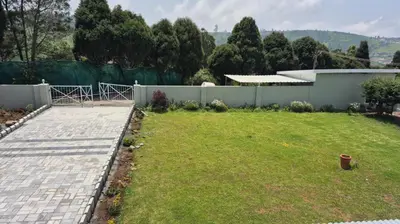 a backyard with a fence and a grass yard at Mountain Top Holiday Home in Ooty