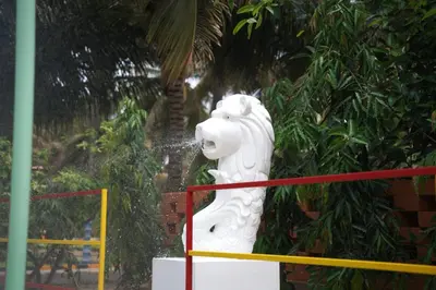 a white statue of a lion in front of some trees at Metro Club Resort in Kāmānayakkanpālaiyam