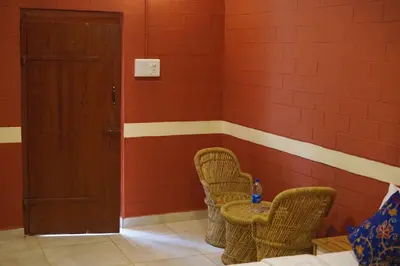 two chairs and a table in a room with red walls at Metro Club Resort in Kāmānayakkanpālaiyam