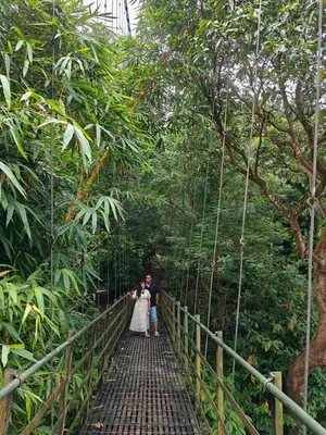 a bride and groom standing on a bridge in the rainforest at Rainy Woods Inn in Neriyamangalam