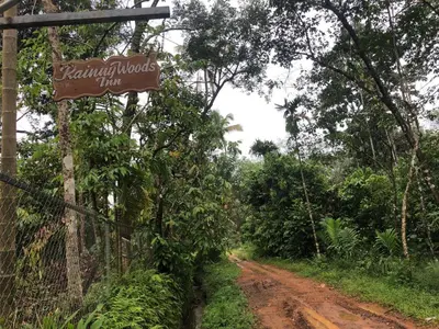 a sign on a fence next to a dirt road at Rainy Woods Inn in Neriyamangalam