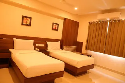 a hotel room with two beds and a window at Hotel Le Palace in Coimbatore
