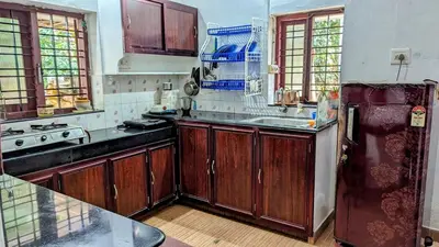 a kitchen with wooden cabinets and a refrigerator at Spacious 2-storey home-4 bedroom in Kunnamkulam