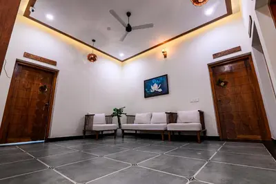 a living room with two chairs and two doors at Dr Indulekhas Ayurvedic Wellness And Rejuvenation in Tellicherry