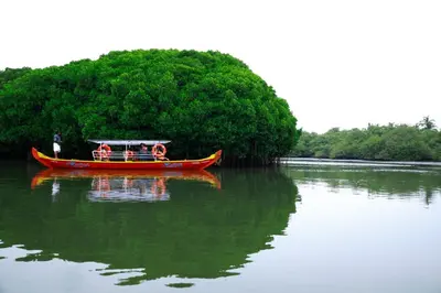 a red boat on the water with a person on it at Kadingis homestay and eco tourism in Kadalundi