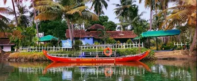 a red boat in the water in front of a house at Kadingis homestay and eco tourism in Kadalundi