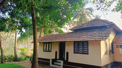 a small house with a roof and some palm trees at Kadingis homestay and eco tourism in Kadalundi