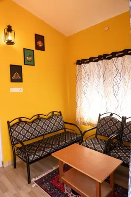 a living room with two chairs and a table at Retro Radiance in Ooty