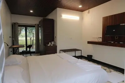 a bedroom with a white bed and a television at Ibex Resorts, Malampuzha - Kava Eco Camp and Caravan Park in Palakkad