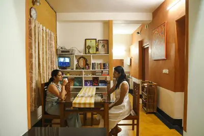 two women sitting at a table in a room at Namastay - Haritha Thara in Kalpetta