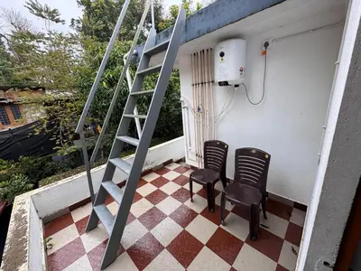 two chairs sitting on a porch with a ladder at Sukhavana home stay suite in Madikeri