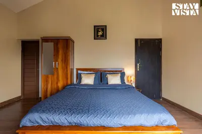 a bedroom with a large bed with a blue comforter at StayVista at Ambrosia access to water stream in Kotagiri