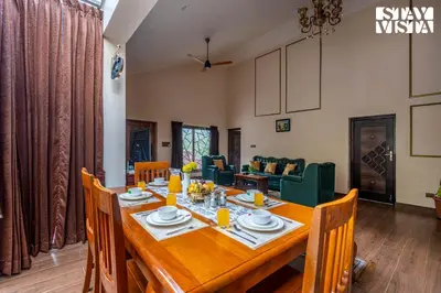 a dining room with a wooden table and chairs at StayVista at Ambrosia access to water stream in Kotagiri