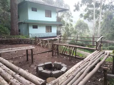 a building with a bunch of logs in front of it at Sahari Villa, Vattavada in Vattavada