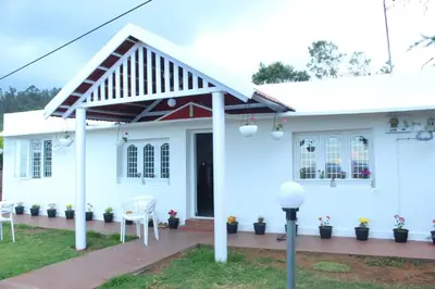 a white house with white chairs in front of it at Hills Dale ooty 3 bhk vintage tea estate villa in Ooty