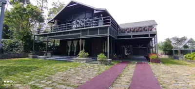 a large house with a balcony and a yard at Coorg Countryside 1BR in Kushālnagar