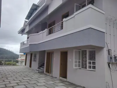 a white building with a balcony and a patio at Little heaven in Ooty