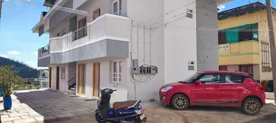 a red car parked next to a building with a scooter at Little heaven in Ooty