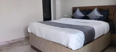 a bedroom with a large bed with white sheets and blue pillows at Little heaven in Ooty