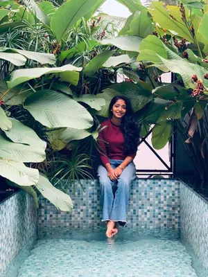 a woman sitting on a wall in front of plants at Cherry Blossoms Chalet in Kozhikode