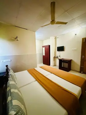 a large room with two beds and a tv at K M S Residency in Tirūr