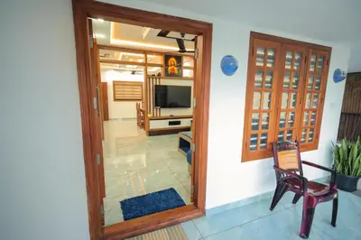 a room with a door and a chair and a television at Wayanadanhuts Home Stay in Sultan Bathery