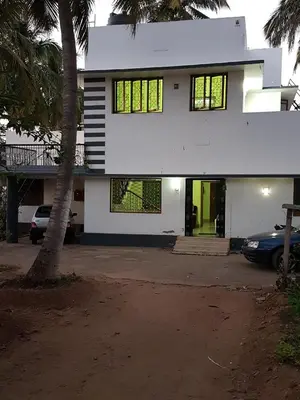 a white house with a car parked in front of it at Anand Bagh in Pollāchi