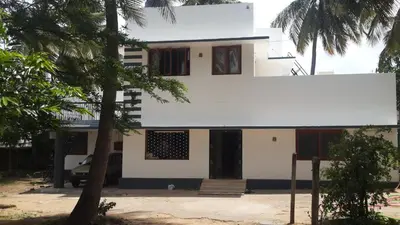 a white house with a tree in front of it at Anand Bagh in Pollāchi