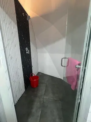 a bathroom with a red bucket next to a door at Rivergreen resort in Athirappally