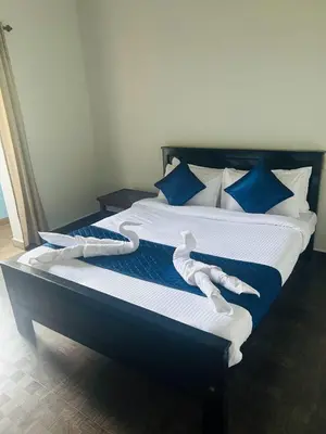 a large bed with blue and white sheets and blue pillows at ROYAL HOLIDAY HOMe in Ambalavayal