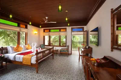 a bedroom with a bed and a table and chairs at Koviloor Resort in Vattavada