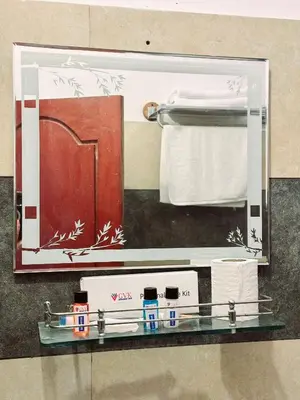 a mirror in a bathroom with towels on a shelf at GVK Holiday Inn in Mysore