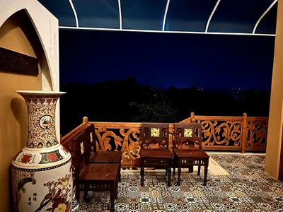a vase sitting on a patio with chairs and a table at Room Marakkech Mazha at Samava Farms Calicut in Kozhikode