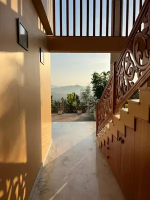 a hallway of a house with a wooden stairway at Room Suvira at Samava Farms Calicut in Kozhikode